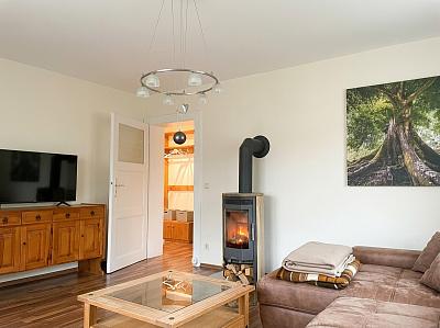Wohnzimmer mit SmartTV, Kaminofen und Schlafsofa