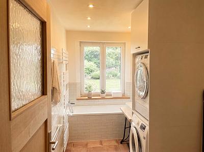 Badezimmer mit Toilette, Wanne, Waschmaschine und Trockner